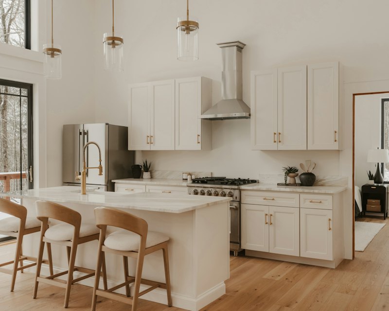 Warm white kitchen with glass and brass pendant lights over the island